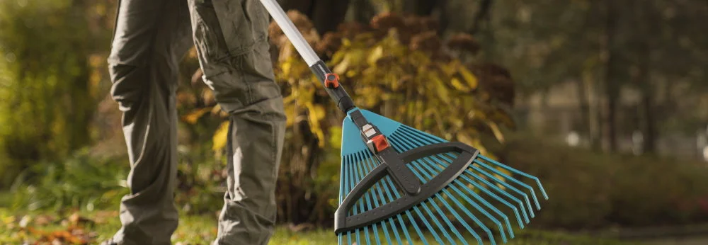 Person mit Laubrechen im Garten